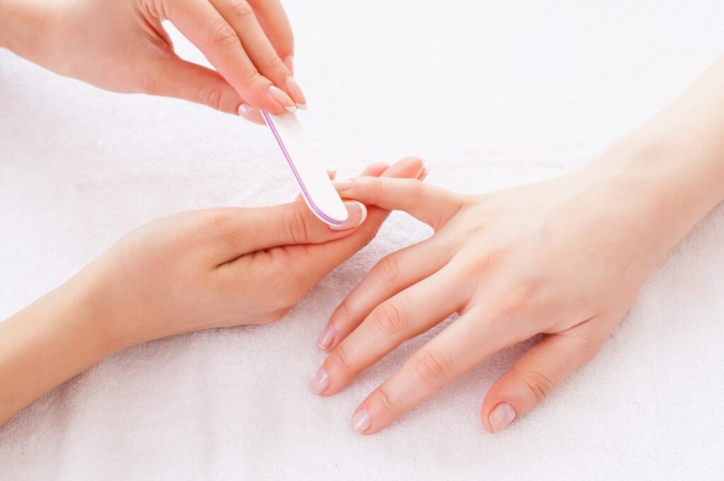 Nail care. Close-up of beautician polishing female nails
